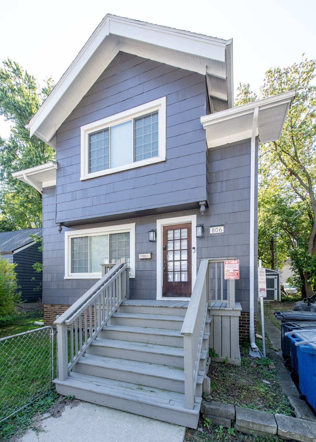 A small blue house with a brown door and a sign on the front.