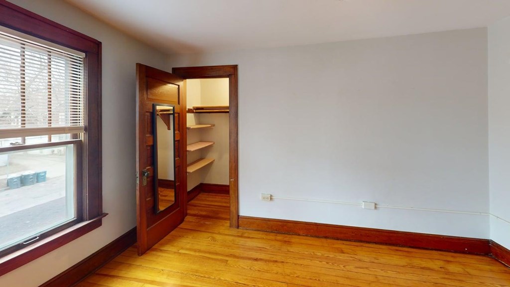 A room with a wooden floor and a door leading to another room.
