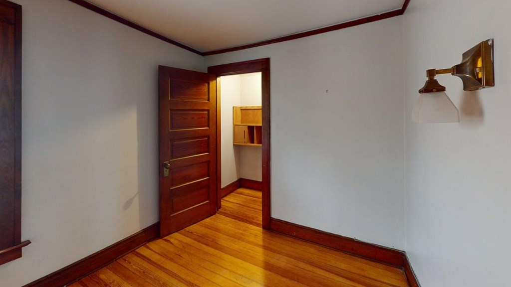 A room with a wooden floor and a door leading to another room.