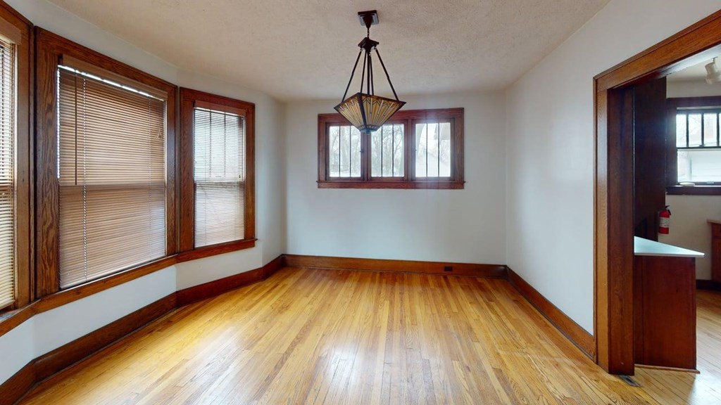 A room with wooden floors and a chandelier hanging from the ceiling.