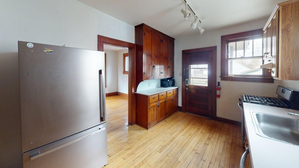 A kitchen with wooden cabinets and a stainless steel refrigerator.