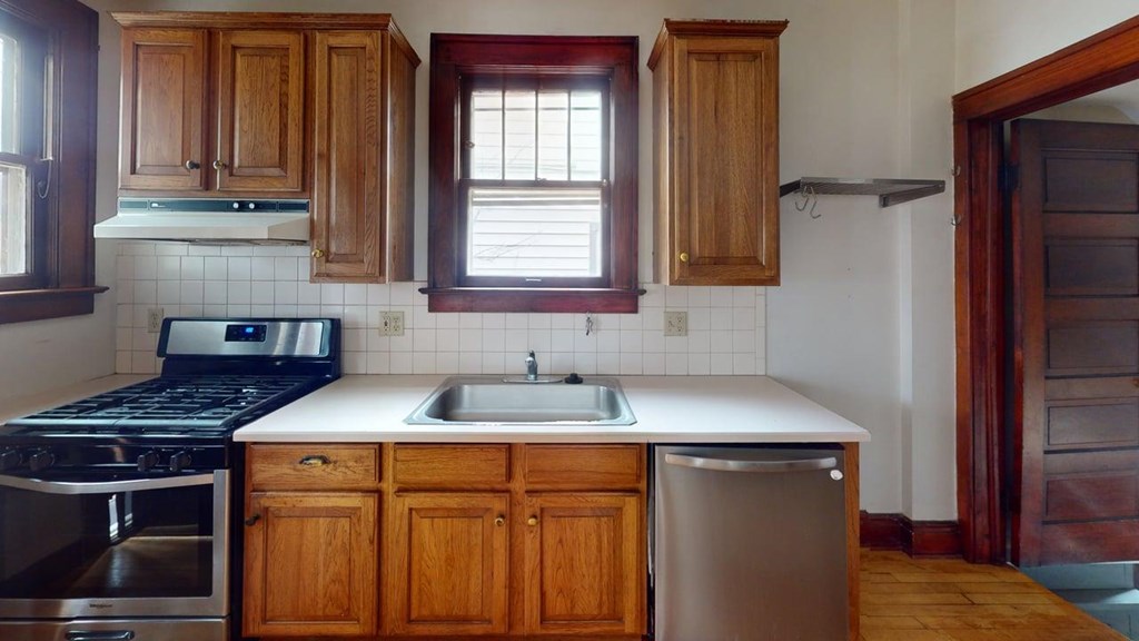 A kitchen with wooden cabinets and a stainless steel dishwasher.