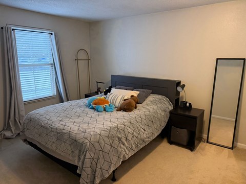 A bedroom with a bed, a mirror, and a window.