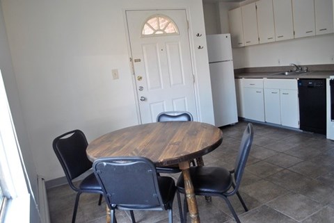 A kitchen with a table and chairs in the foreground.