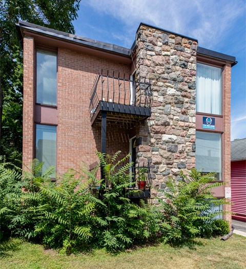 A red brick house with a balcony and a stone chimney.