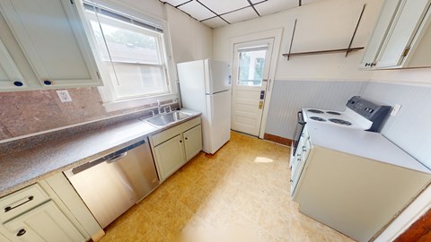 A kitchen with white appliances and a window.