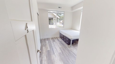 A white bedroom with a bed and a window.