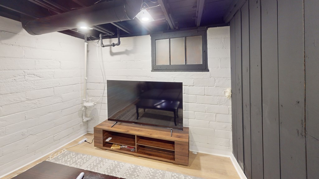 A white brick wall with a television and a wooden stand below it.