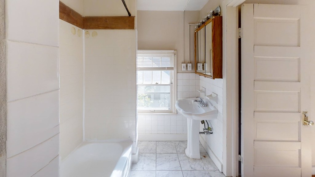 A white bathroom with a sink and mirror.