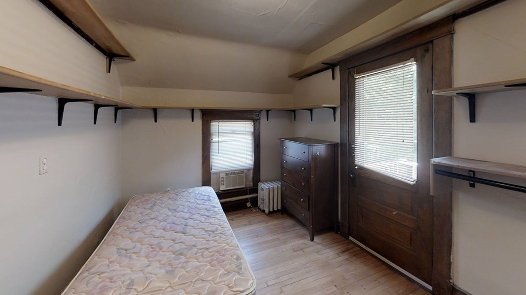 A bedroom with a bed, dresser, and window.