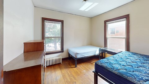 A bedroom with a bed, a window, and a radiator.