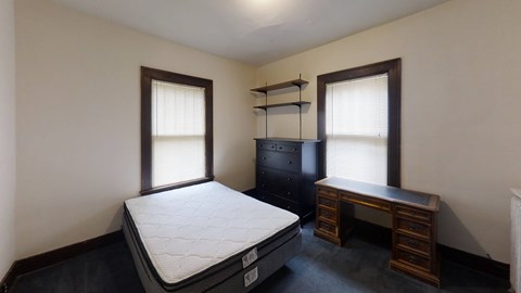 A bedroom with a bed, desk, and shelves.