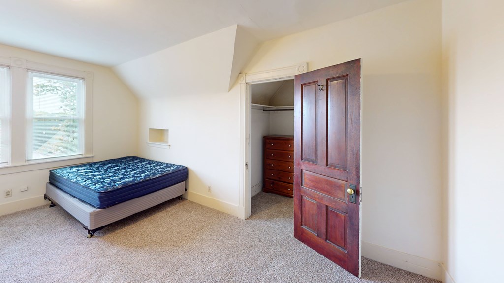 A bedroom with a bed, a dresser, and a door.