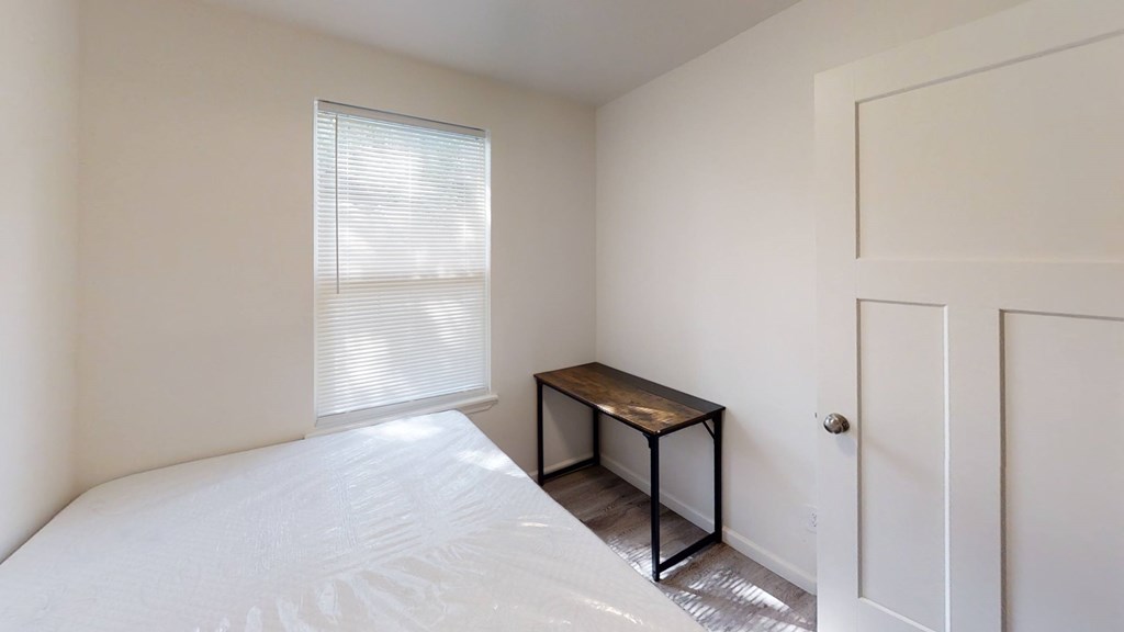 A small room with a bed, a table and a door.