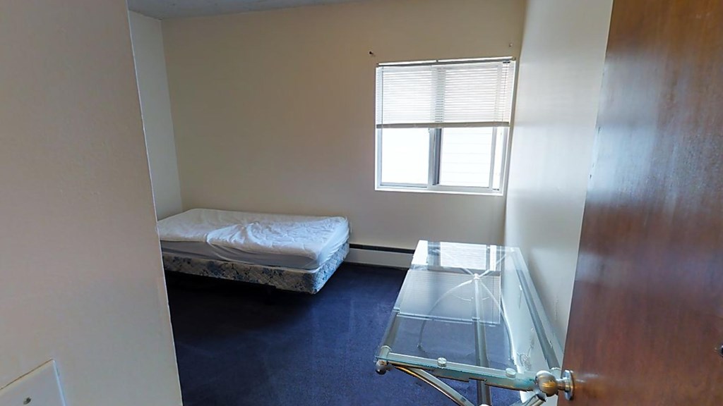 A small room with a bed and a glass table.