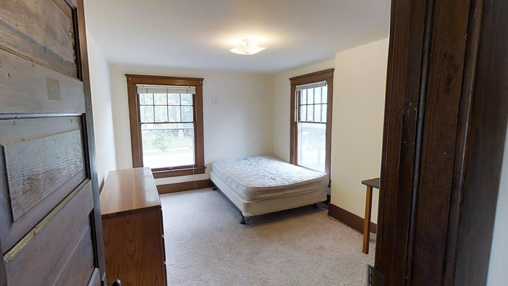 A bedroom with a bed, dresser, and window.