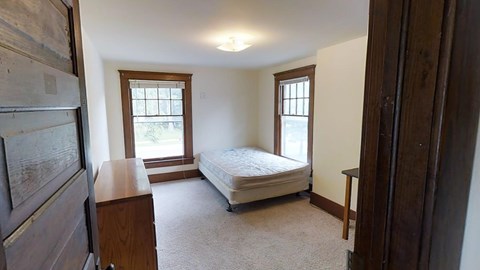 A bedroom with a bed, dresser, and window.