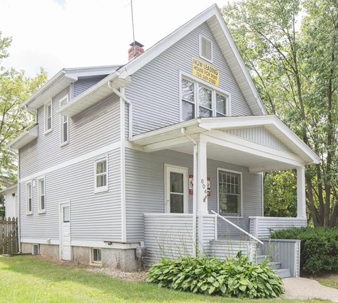 A house with a sign that says "NO LEANING HOUSE" on the front.