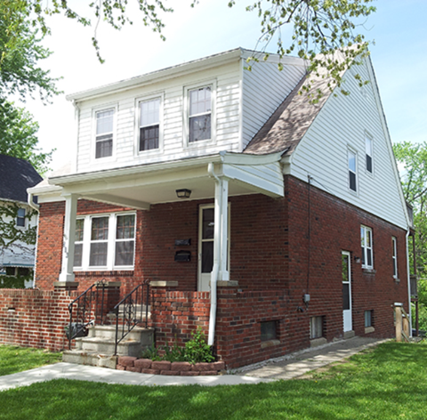 A white house with a red brick base and a porch.