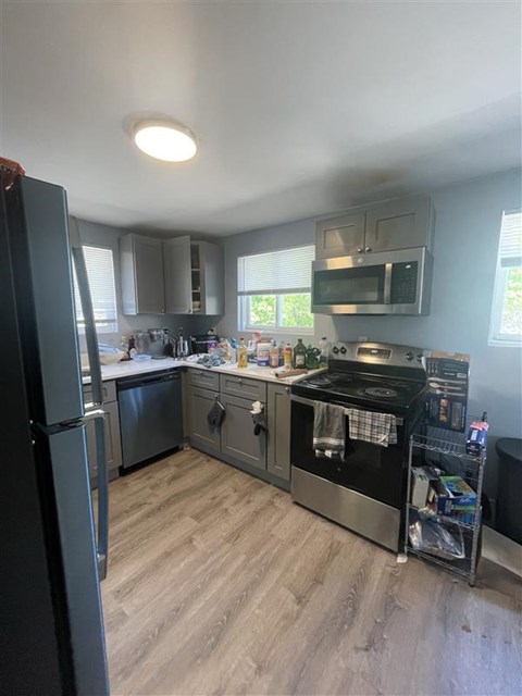 A kitchen with a black refrigerator and stove top oven.