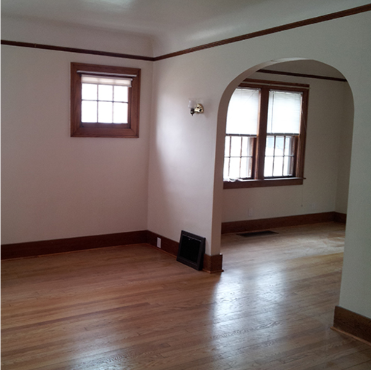 A room with wooden floors and two windows.