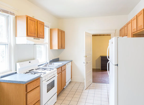 A kitchen with white appliances and wooden cabinets.