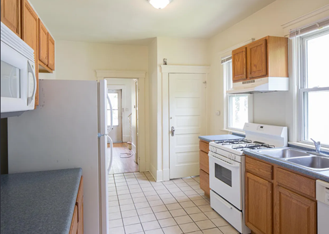 A kitchen with white appliances and wooden cabinets.