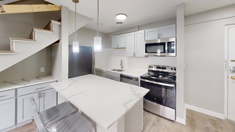 A modern kitchen with a stainless steel refrigerator, microwave, and oven.