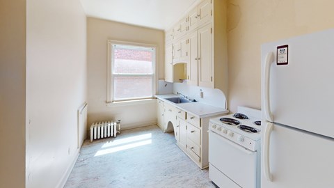 A white kitchen with a fridge, stove, and sink.