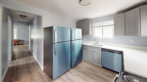 A kitchen with a blue refrigerator and wooden floors.