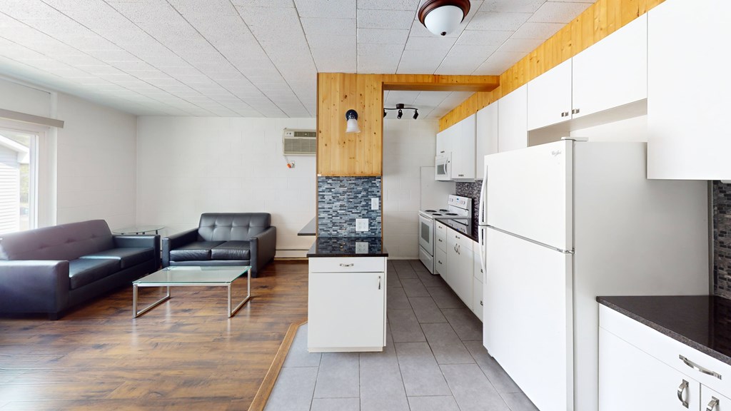 A modern kitchen with white appliances and a wooden accent wall.