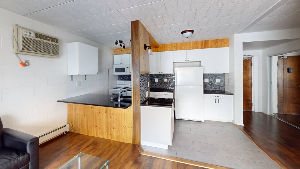 A kitchen with a black counter top and white cabinets.
