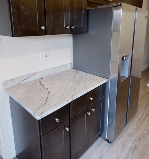 A kitchen with a marble countertop and a refrigerator.
