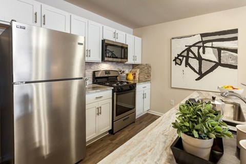 A modern kitchen with a stainless steel refrigerator and white cabinets.