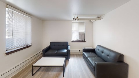 A black sofa sits in a white room with a coffee table in front of it.