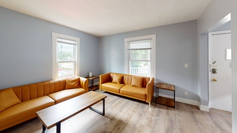 A living room with a yellow couch and a wooden coffee table.