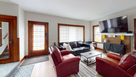 A living room with red leather chairs and a black couch.