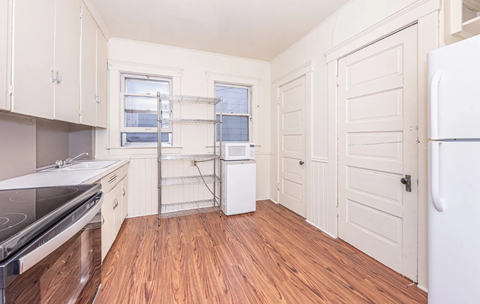 A kitchen with white appliances and wooden floors.