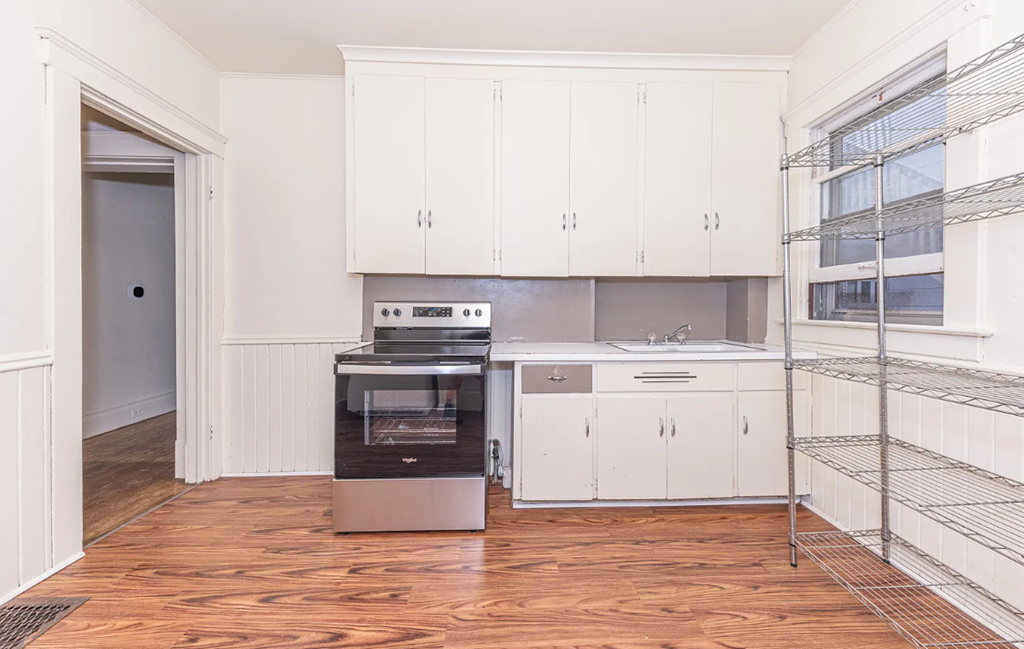 A kitchen with white cabinets and a wooden floor.