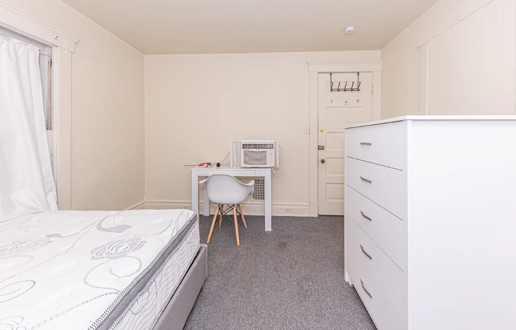 A bedroom with a bed, desk, and chair.