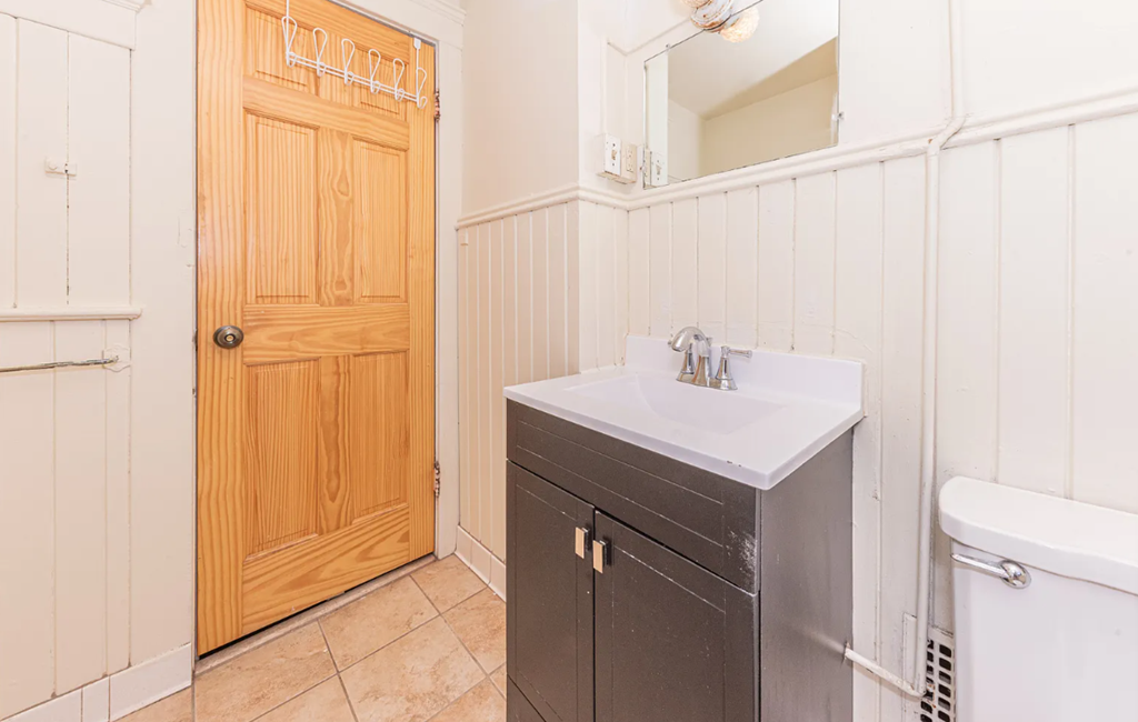 A bathroom with a wooden door and a white sink.