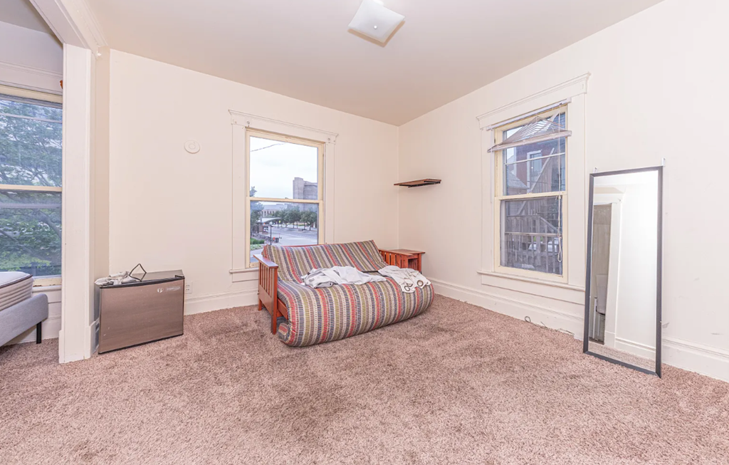 A bedroom with a bed, dresser, and window.