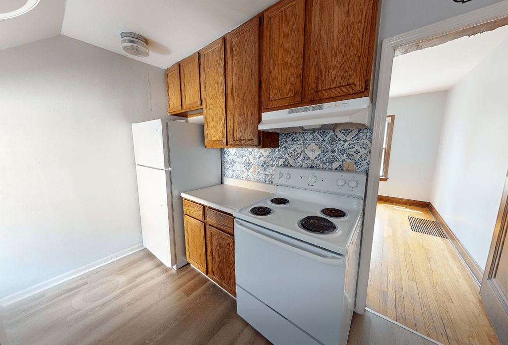 A kitchen with a white stove and wooden cabinets.