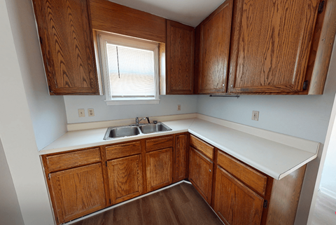 A kitchen with wooden cabinets and a window above the sink.