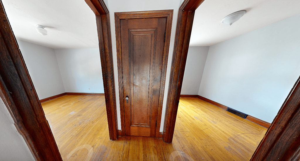 A wooden door is in the middle of a room with wooden floors.