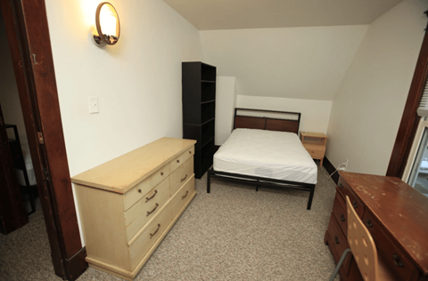 A bedroom with a bed, dresser, and a nightstand.