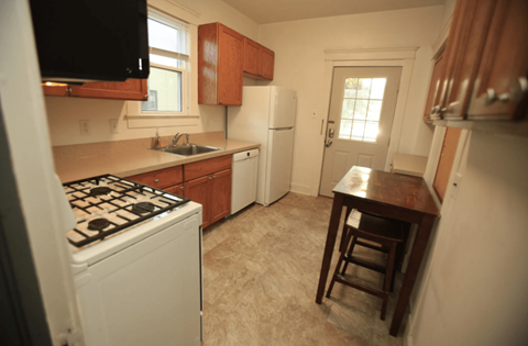 A kitchen with a white stove and wooden cabinets.