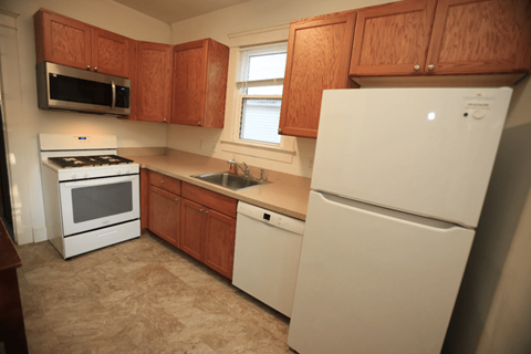 A kitchen with a white fridge, stove, and microwave.