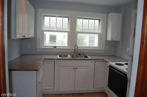 A kitchen with white cabinets and a granite countertop.