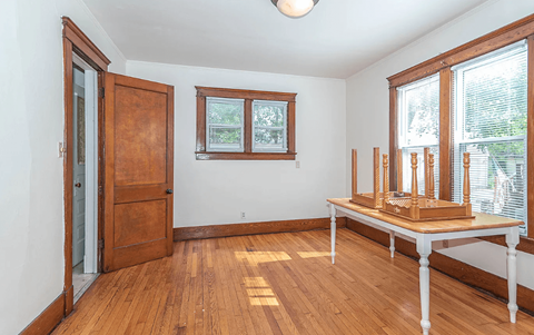 A room with a wooden floor and a table with a few objects on it.